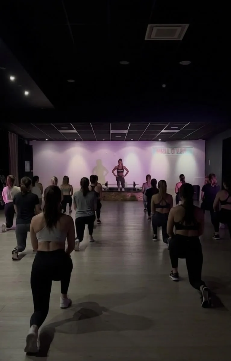 Cours collectif entre femmes chez Walgym : la coach face au groupe dans la salle éclairée en rose